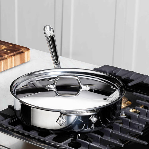 Close-up of the All-Clad D3 Stainless Sauté Pan's handle and rim on a kitchen counter
