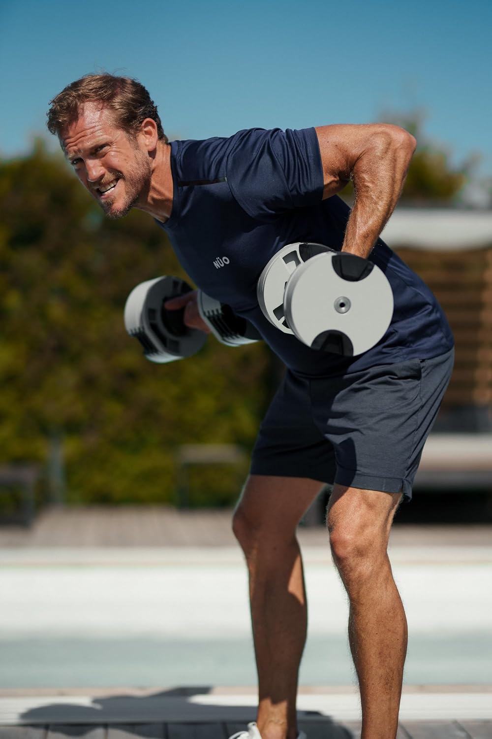 Man doing a bent-over row outdoors with a NUOBELL adjustable dumbbell