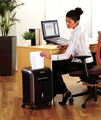 Woman feeding a document into the Fellowes Powershred 79Ci beside her desk in an office setting