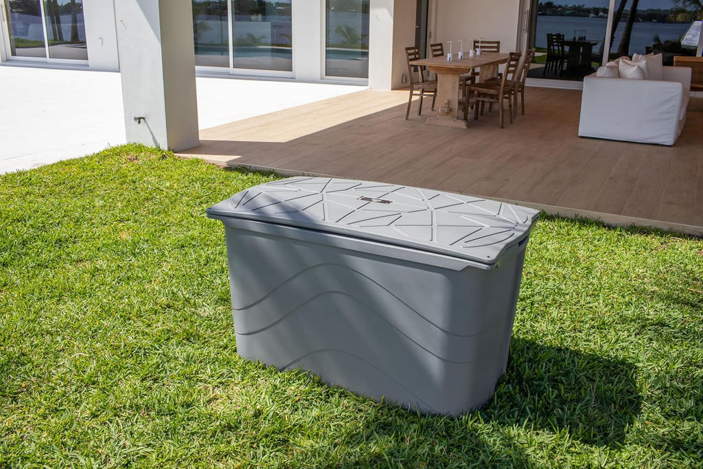 Grey Frozin 400 cold plunge tub closed with its insulated lid on, sitting on a lawn outside a modern waterfront home
