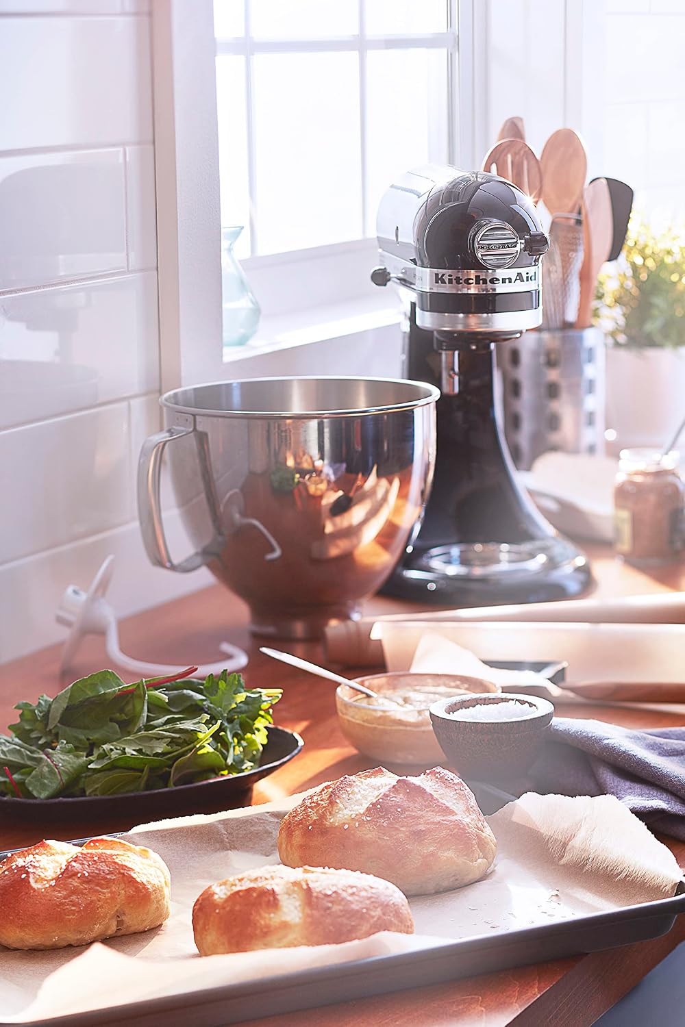 KitchenAid Artisan 5-Qt Stand Mixer in silver on a kitchen counter with baked bread nearby