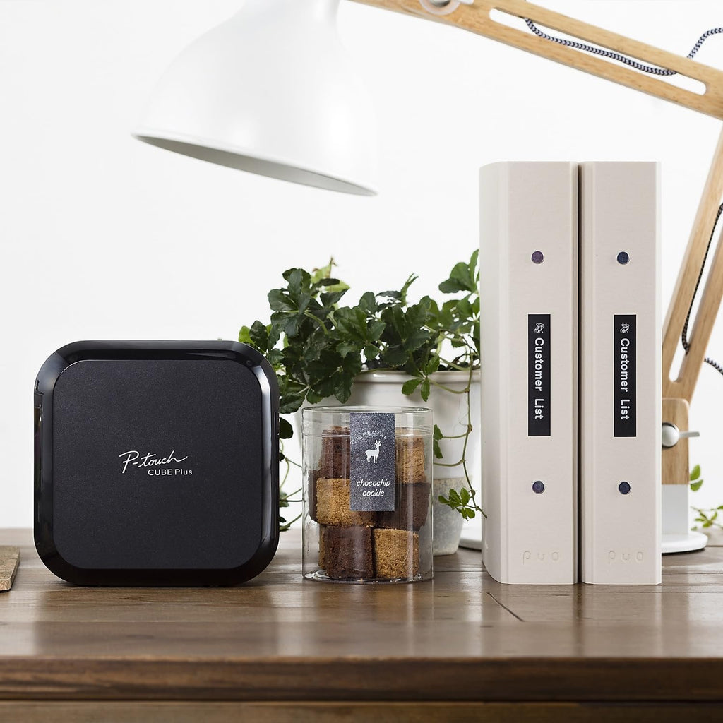 Brother P-touch CUBE Plus Label Maker on a shelf with plants and labeled storage jars