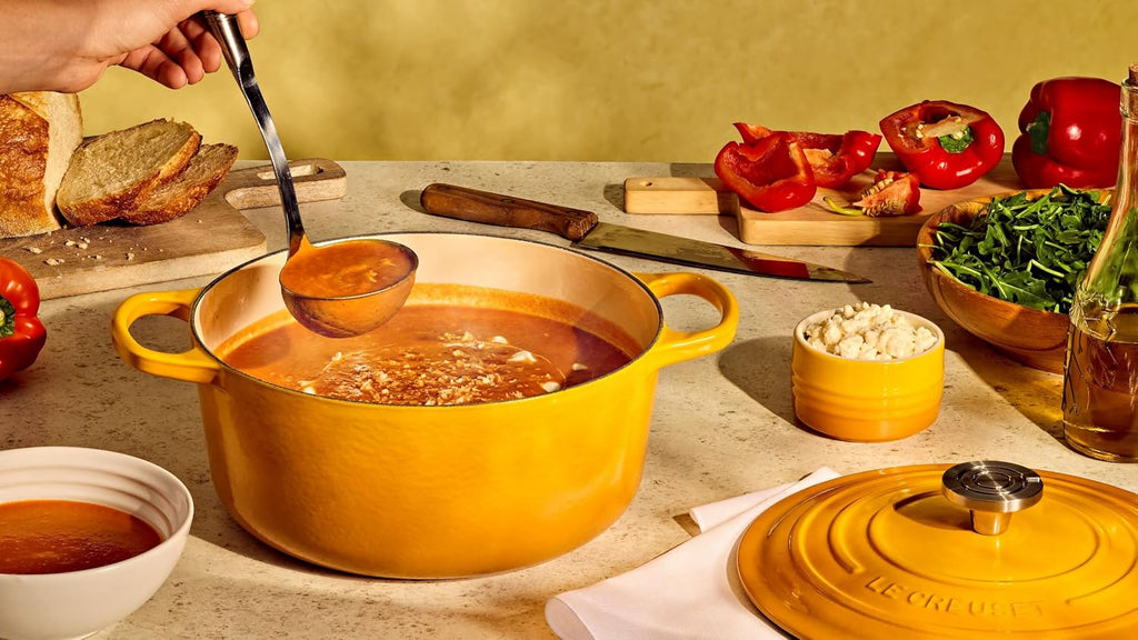 Le Creuset Signature Round Dutch Oven in a mustard yellow finish, filled with food as part of a table spread
