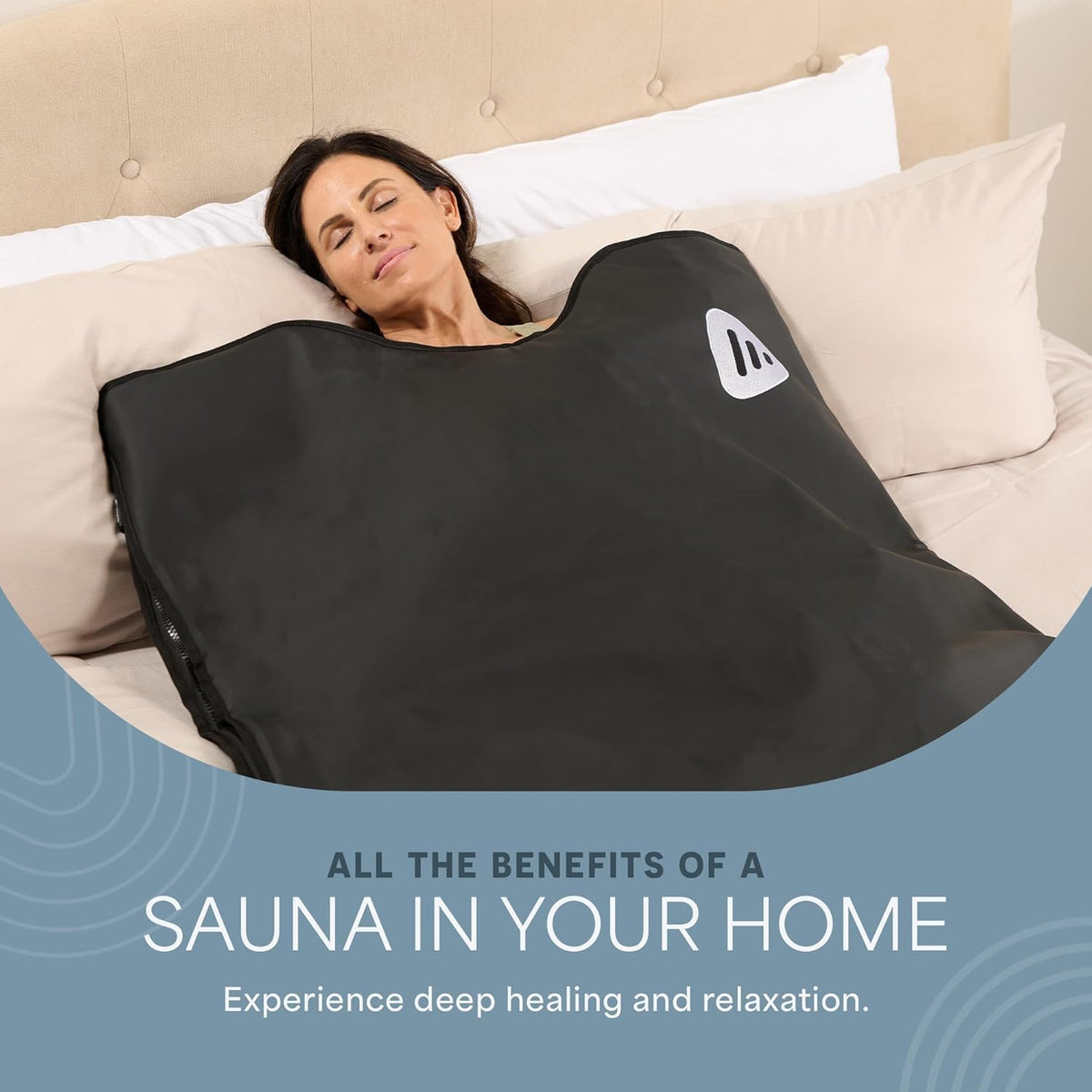 Woman resting on a bed wrapped in a black Lifepro RejuvaWrap infrared sauna blanket for at-home relaxation