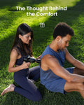 Woman using a RENPHO Active Thermacool 2 massage gun on a man's shoulder while sitting on the grass outdoors
