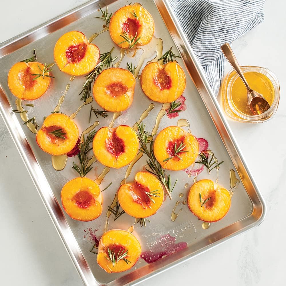 Roasted halved peaches with rosemary on a Nordic Ware Natural Aluminum Sheet Pan