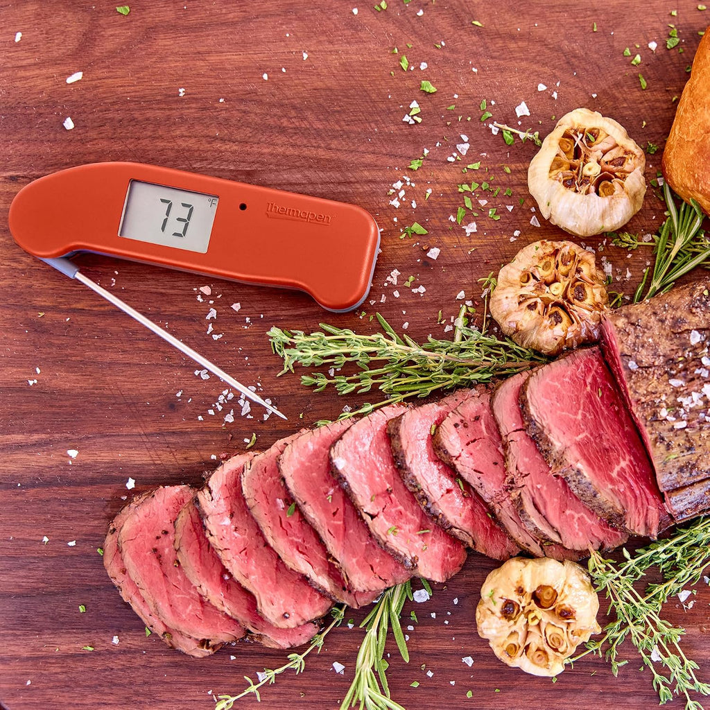 ThermoWorks Thermapen ONE in red, inserted into a sliced beef roast with rosemary and roasted garlic