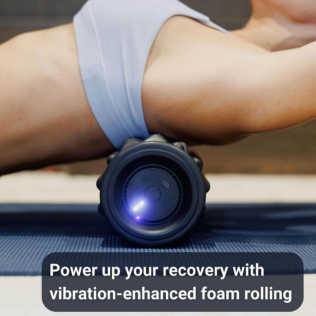 Person using the VibePro Flow vibrating foam roller on a yoga mat, with its light indicator glowing