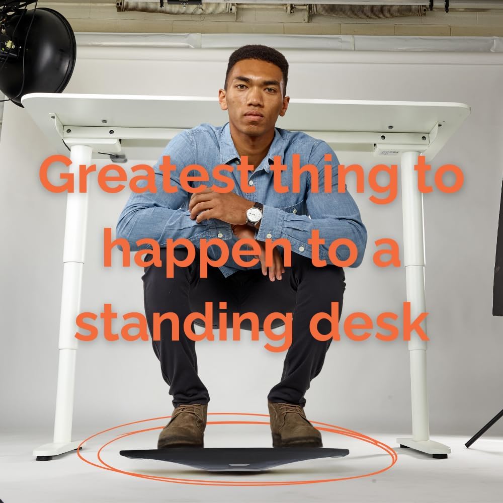 Man crouching on a FluidStance balance board under a standing desk, text reads Greatest thing to happen to a standing desk